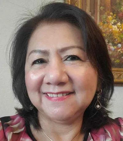 Baby Quintero smiling, with shoulder length dark hair.